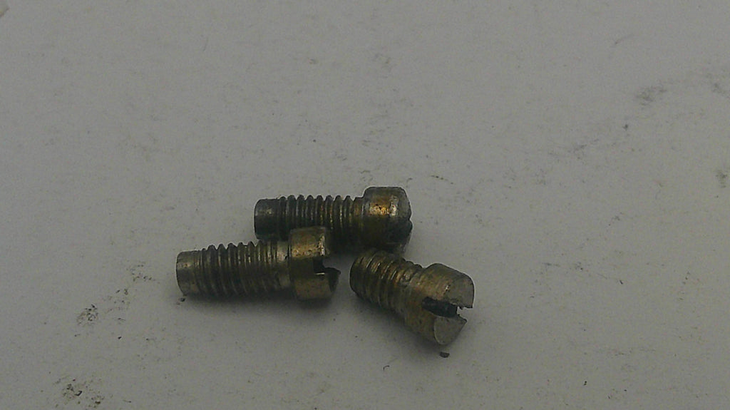 Three small brass screws on a light gray surface