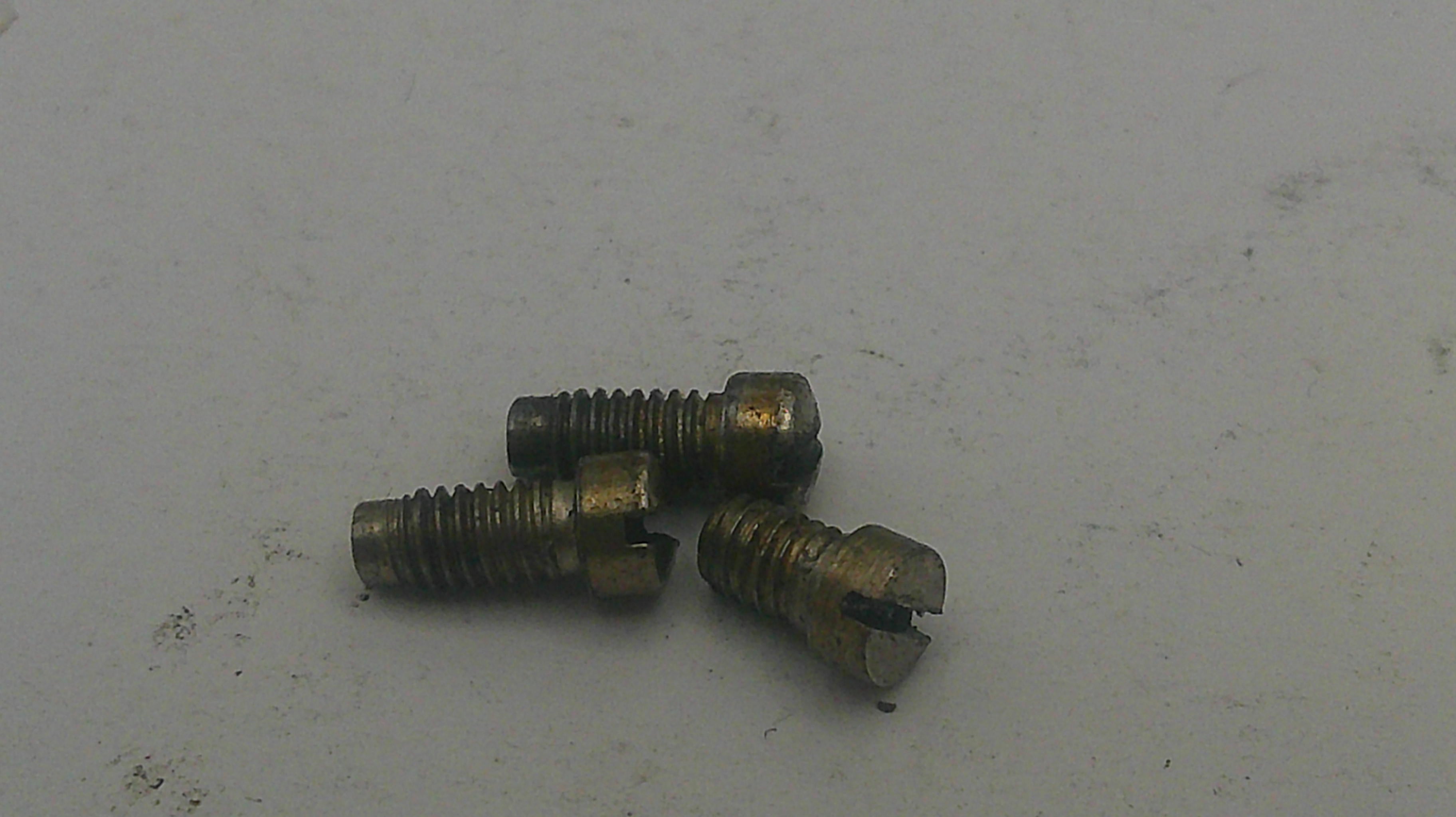Three small brass screws on a light gray surface