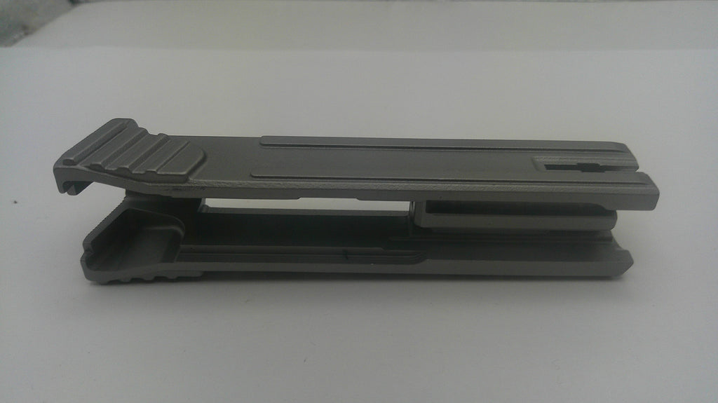A dark gray plastic clip or fastener with a textured grip on the left, photographed on a plain light gray background.