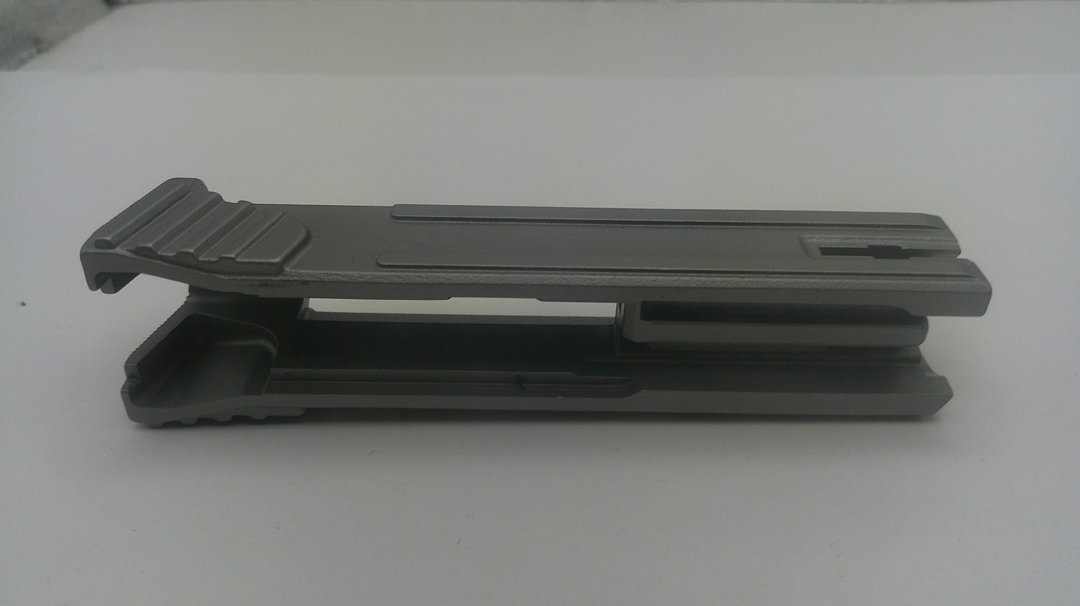 A dark gray plastic clip or fastener with a textured grip on the left, photographed on a plain light gray background.