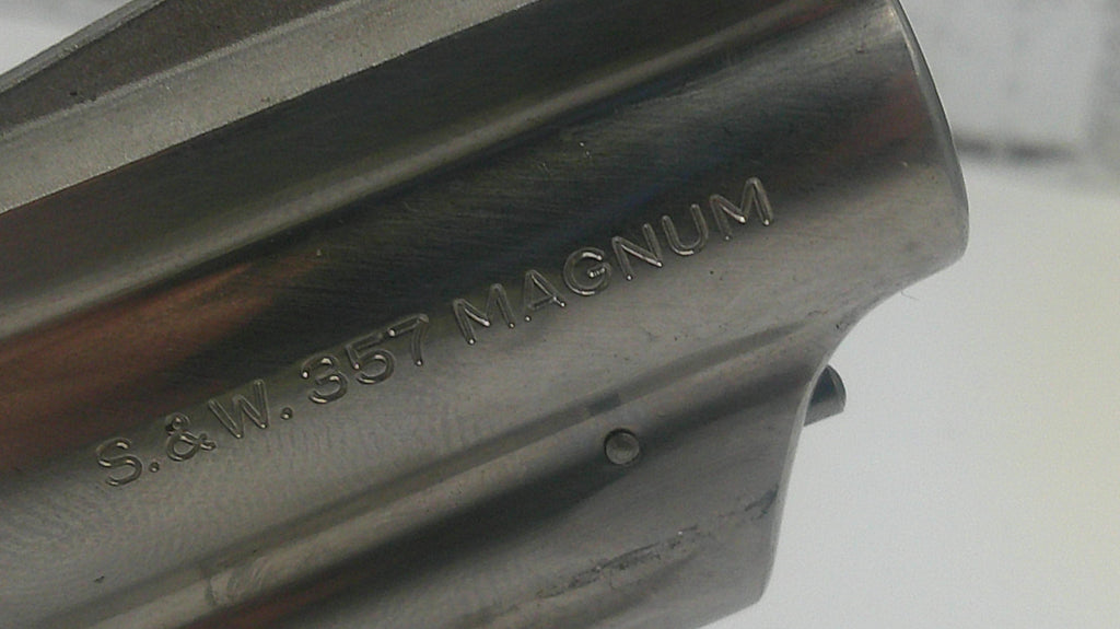 Close-up of a metallic object with 'S.&W. 357 Magnum' engraving on a blurred background