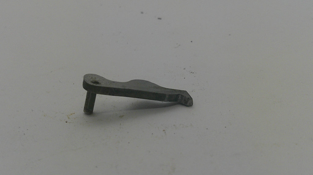A small dark metal hardware piece, possibly a bracket or latch component, shown on a plain light gray surface.