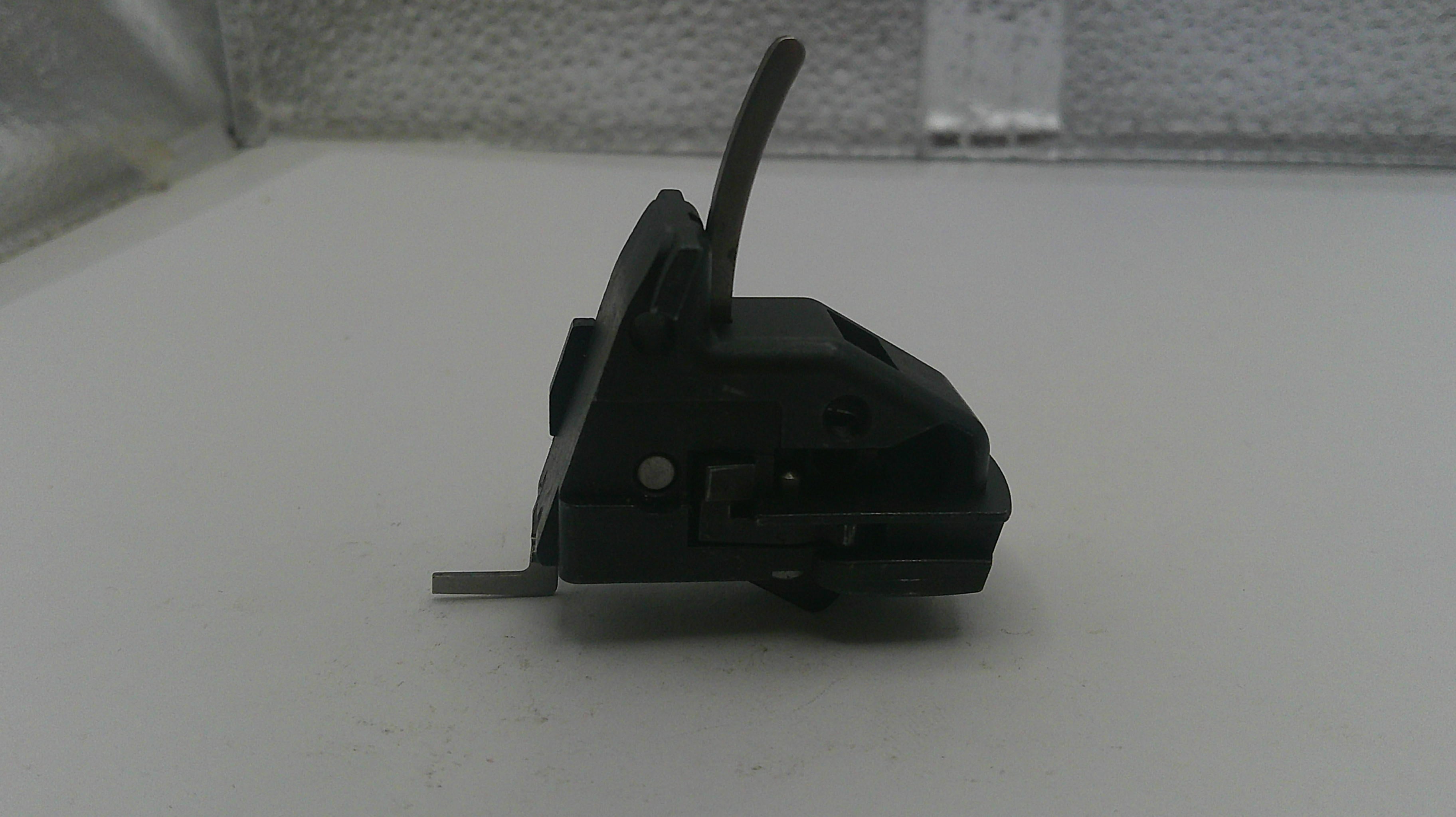 Black mechanical component on a white surface with a blurred background