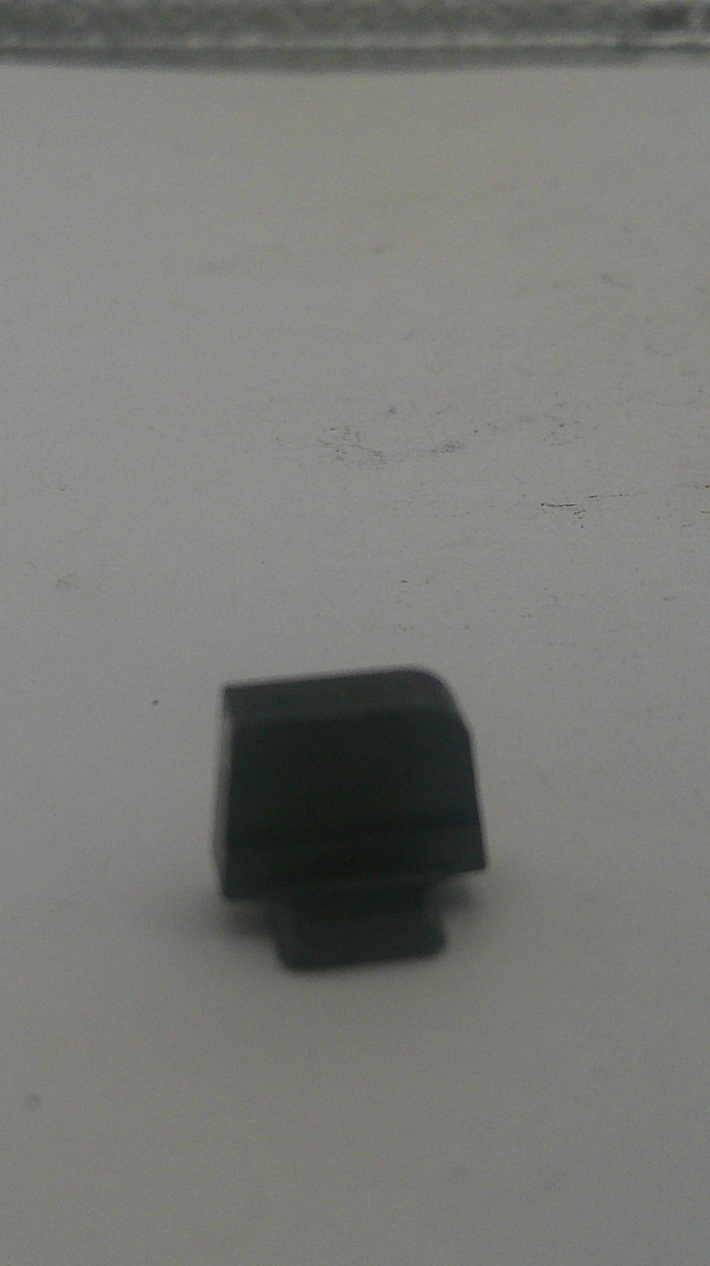 A small black plastic hardware component, possibly a knob, cap, or connector piece, shown against a plain light gray background.
