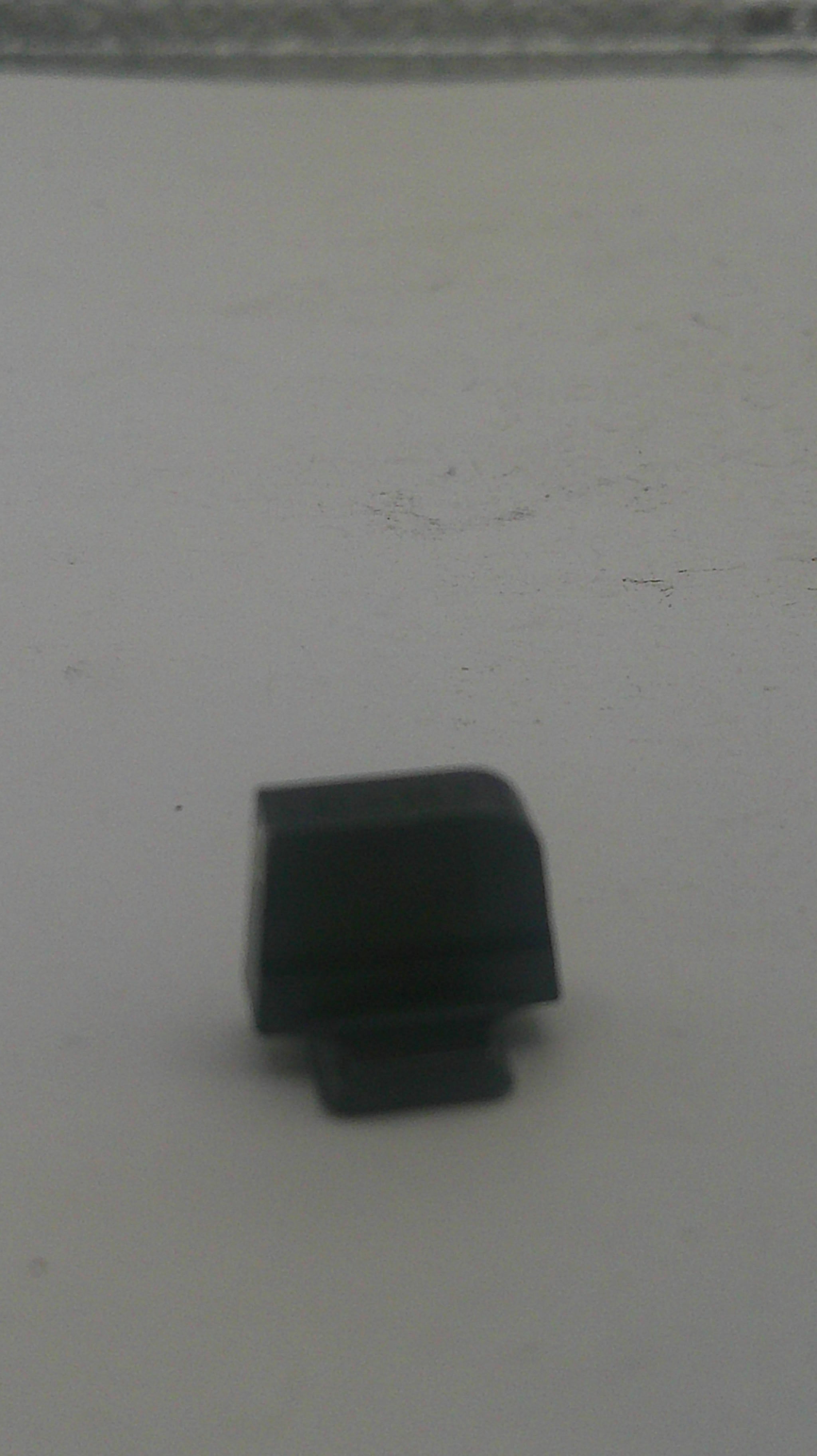 A small black plastic hardware component, possibly a knob, cap, or connector piece, shown against a plain light gray background.