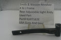 A used black metal part for a Smith & Wesson revolver rear adjustable sight body, displayed on a clear stand with a white label card showing part details.
