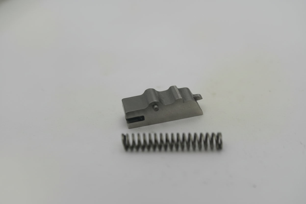 Small mechanical component and spring on a white surface
