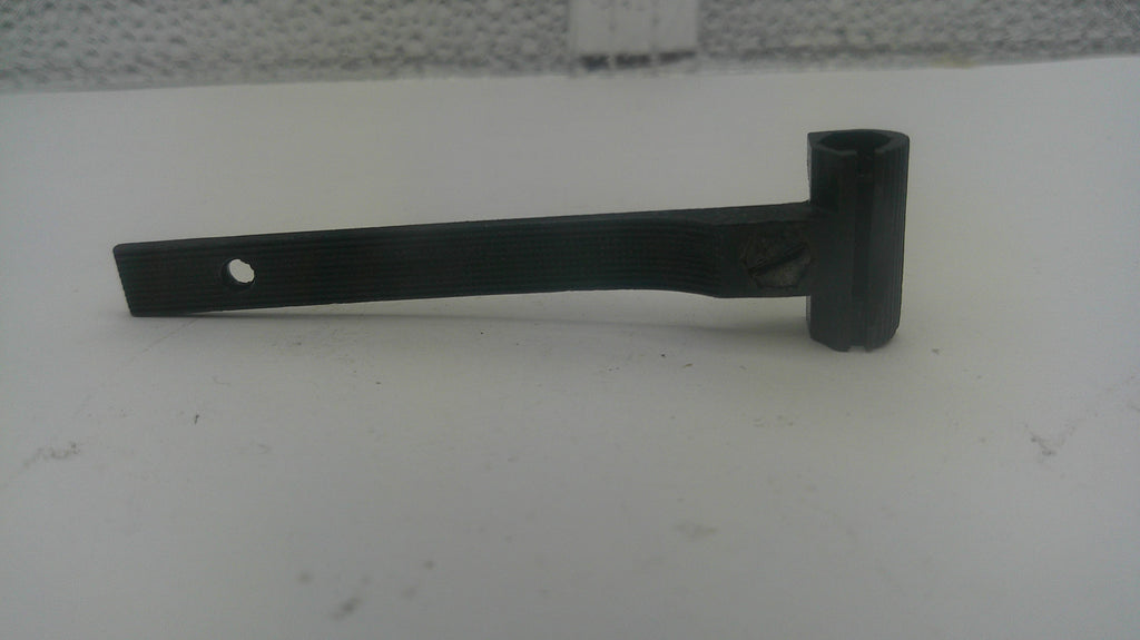 A black metal pipe bend with a cylindrical shank and a single hole on the flat end, resting on a white surface.
