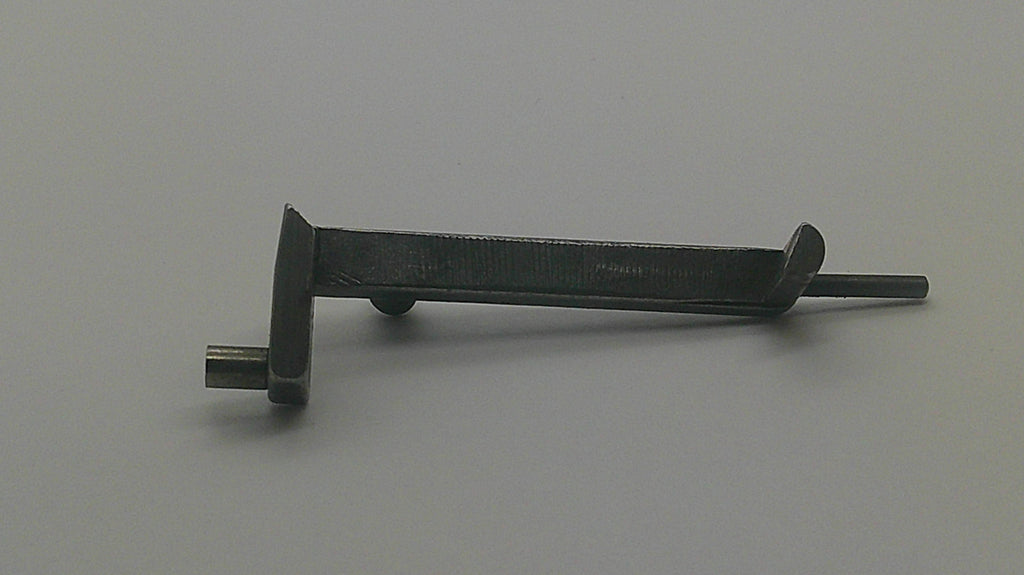 A dark metal tool or hardware piece with a flat rectangular head and a long pointed stem, photographed on a plain light gray background.