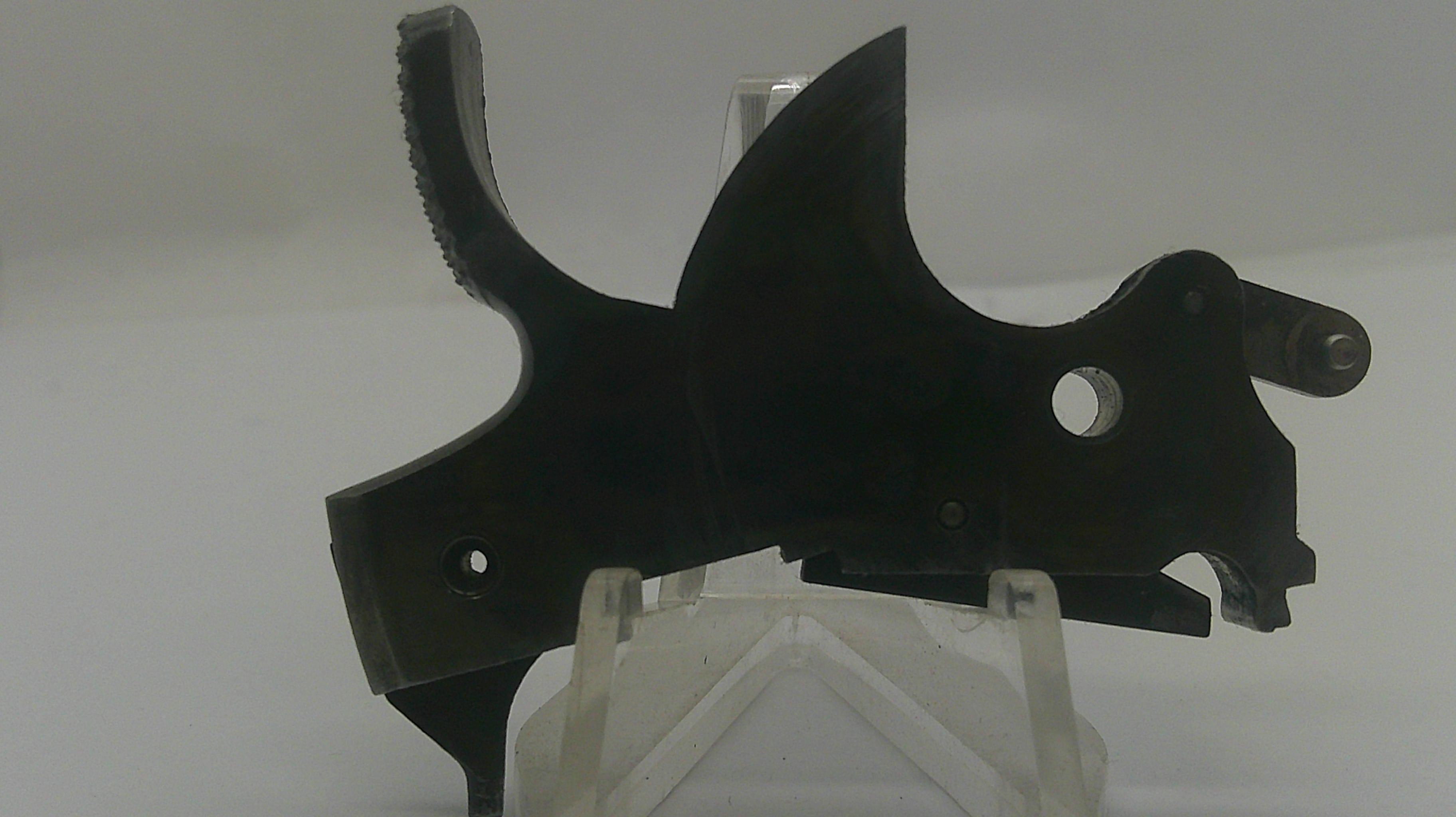 A black metal firearm receiver or grip component displayed on a clear acrylic stand against a plain light gray background.