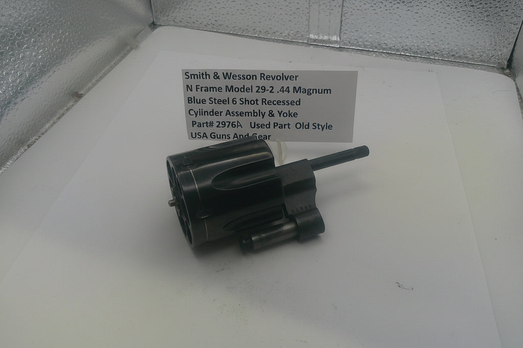 Cylindrical gun part on a white surface with a label