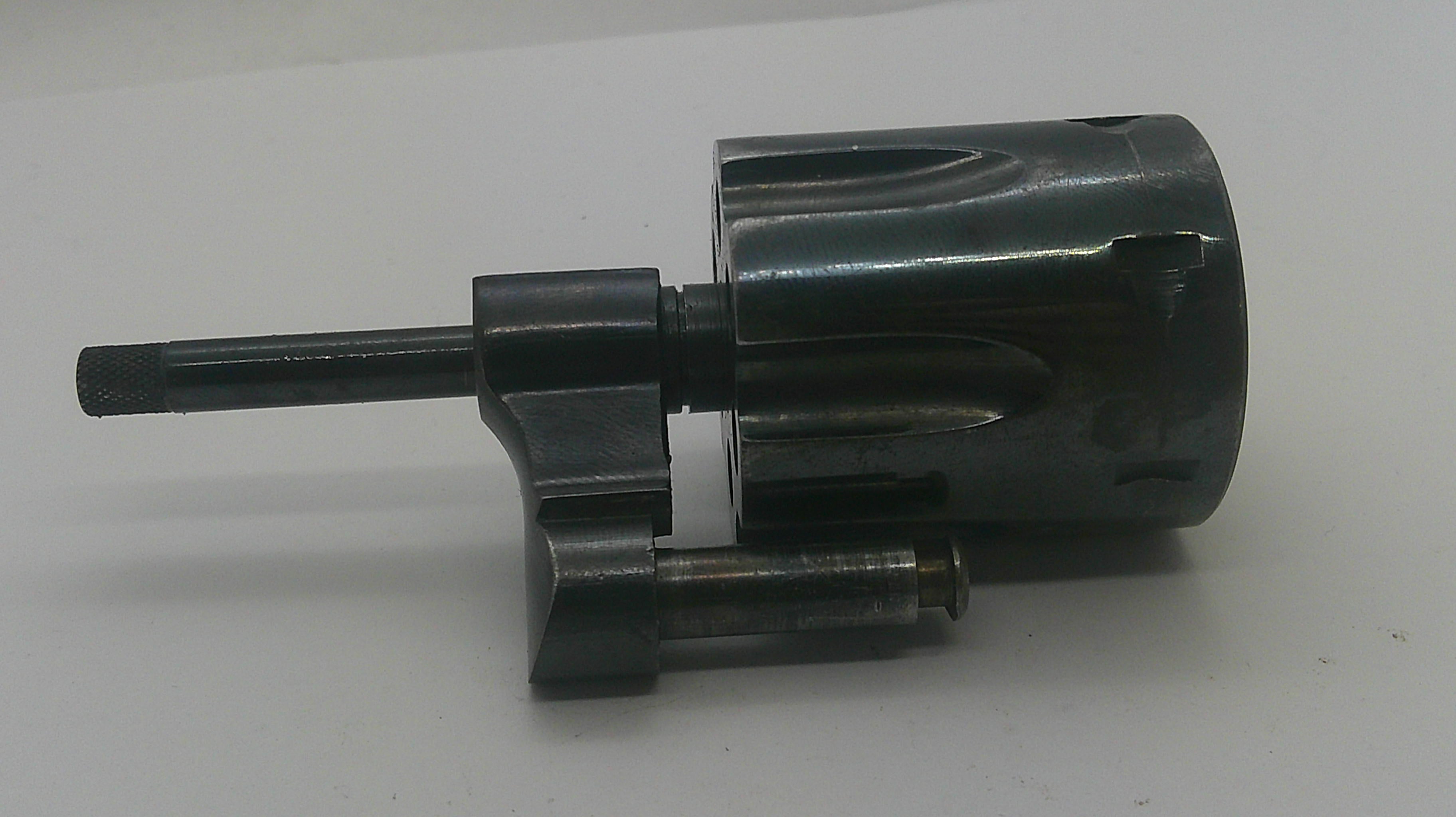 A dark metallic mechanical component or tool part with a cylindrical body and protruding shafts, photographed on a plain light background.