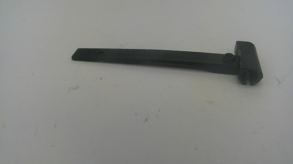 A black plastic replacement part, likely a handle or bracket, lying on a plain off-white surface.