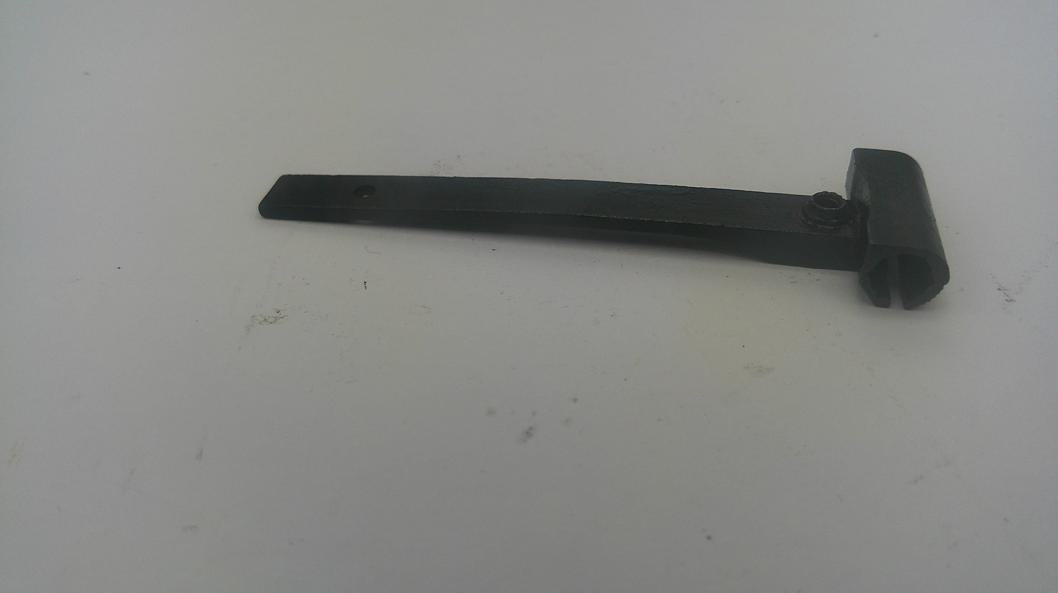A black plastic replacement part, likely a handle or bracket, lying on a plain off-white surface.