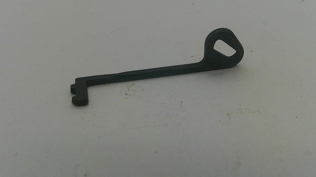 A small black plastic or metal key-shaped tool with a loop at one end, placed on a plain off-white surface.
