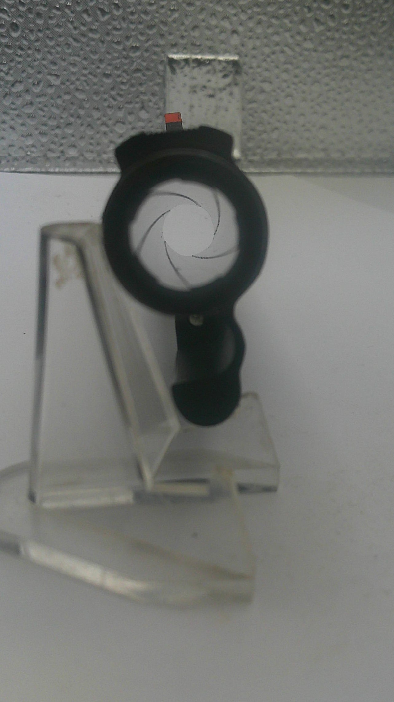 Close-up of a camera lens on a white surface with a textured gray background