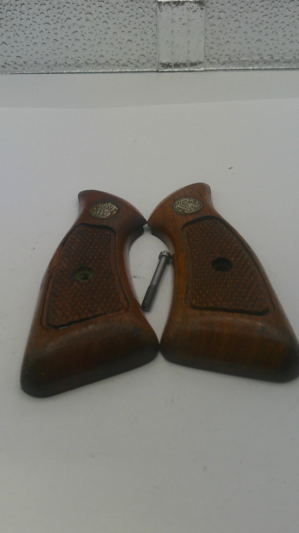 Pair of brown gun grips on a textured white surface
