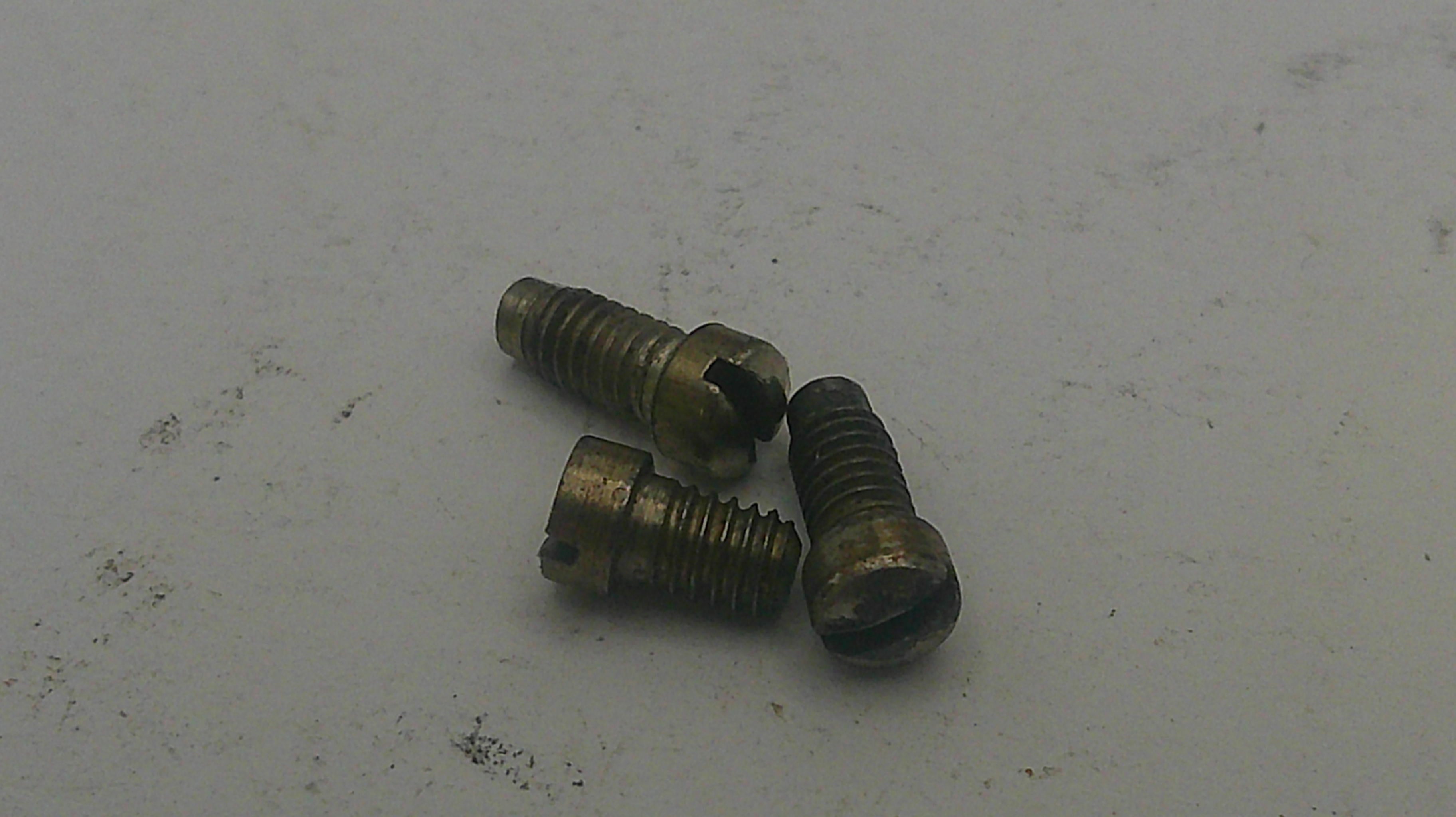 Three brass screws on a light gray background