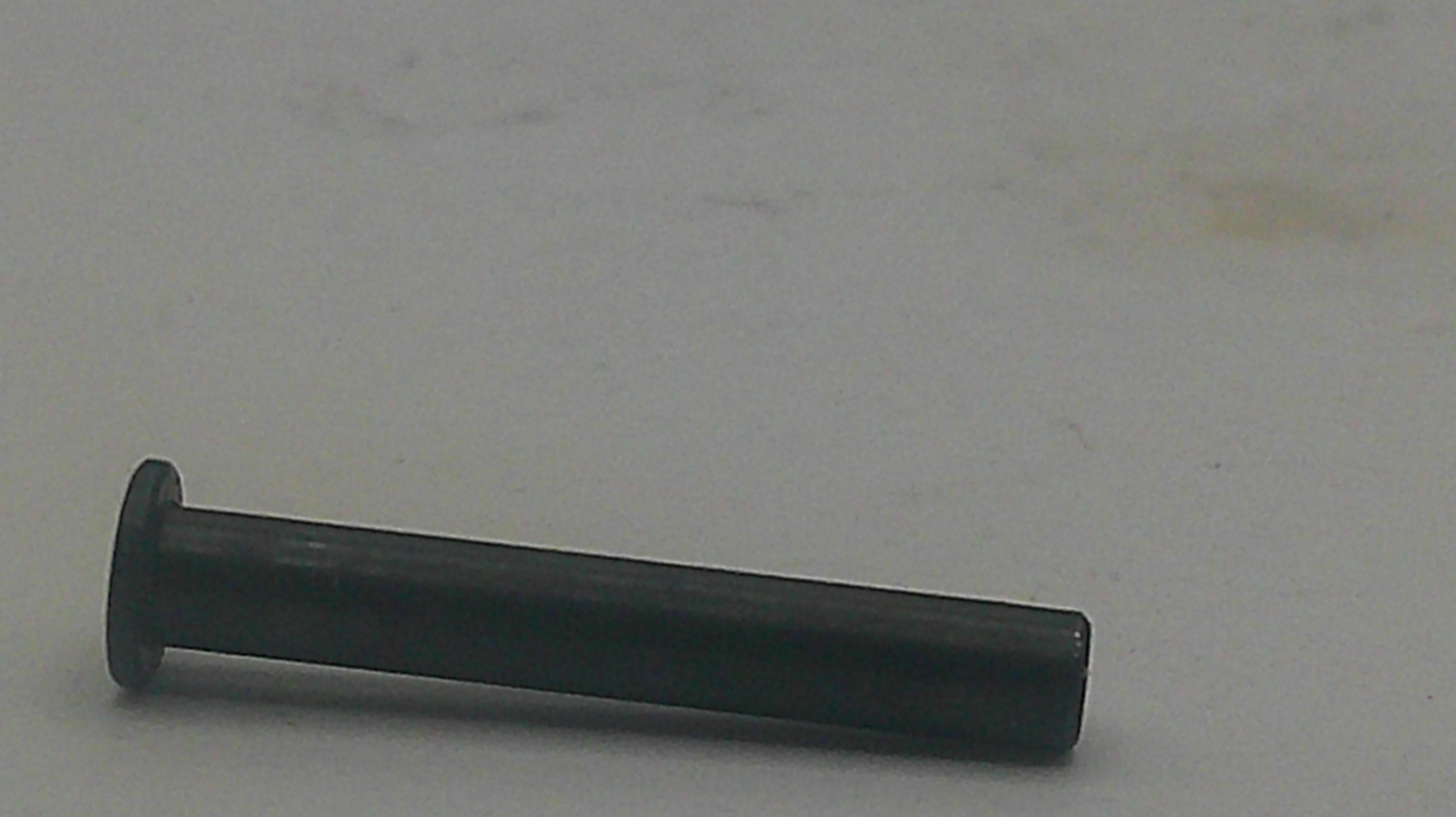 A single black metal rivet or pin with a flat round head, lying horizontally on a plain light gray surface.