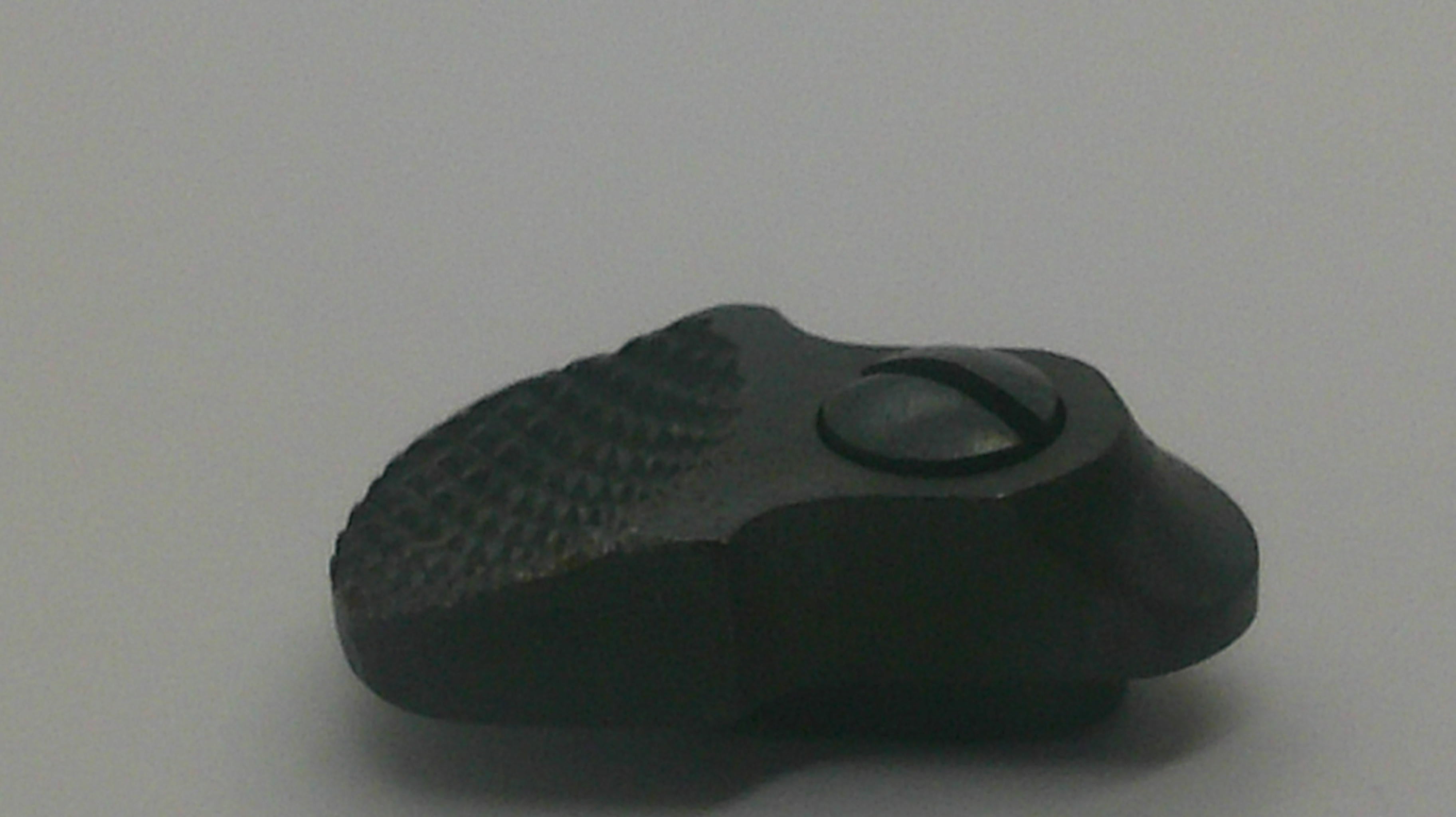 A small black plastic or rubber knob with a textured surface and a circular cutout, photographed on a plain light gray background.