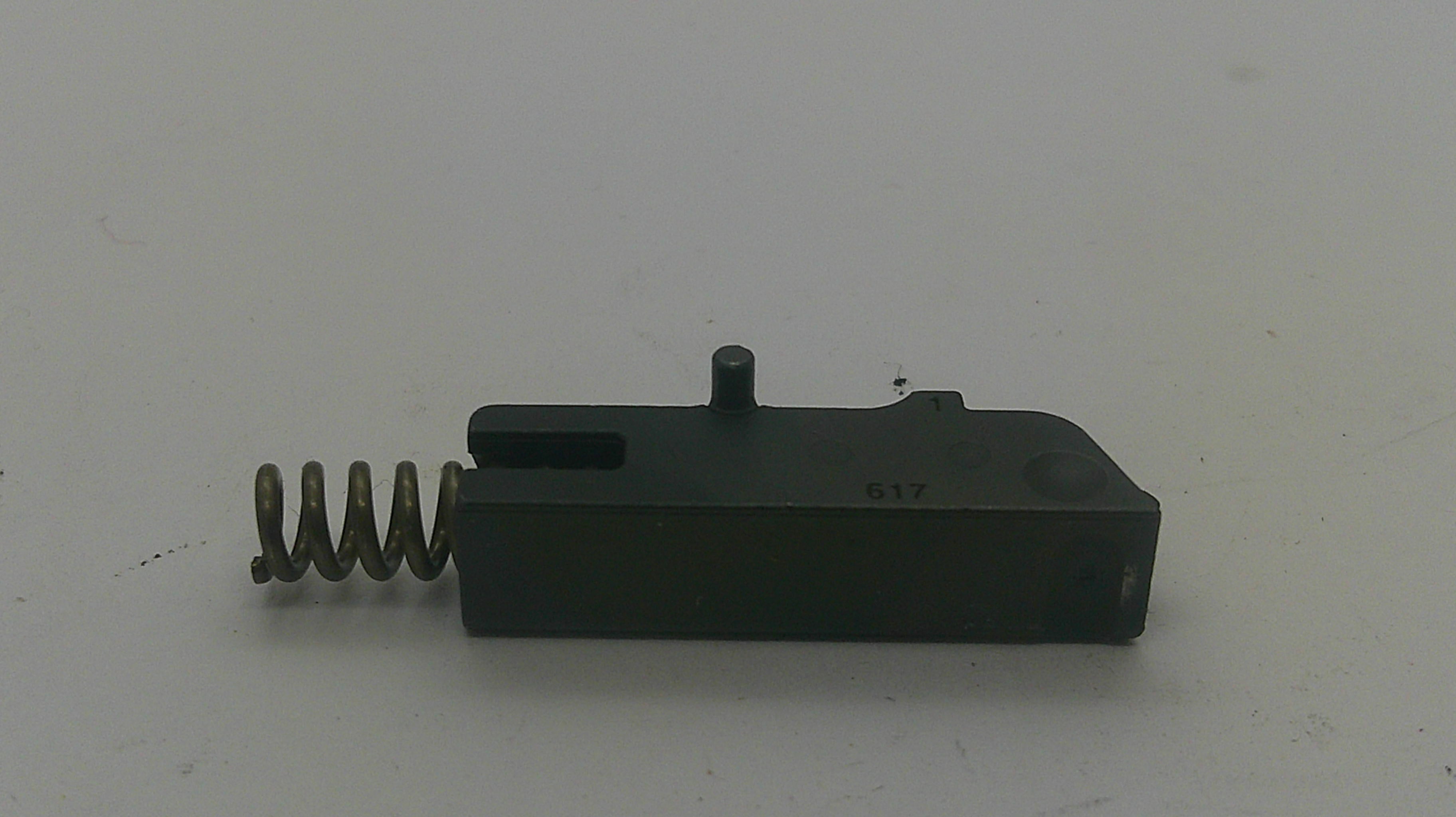 A black metal and spring trigger component, likely a firearm safety part, photographed on a plain light gray background.