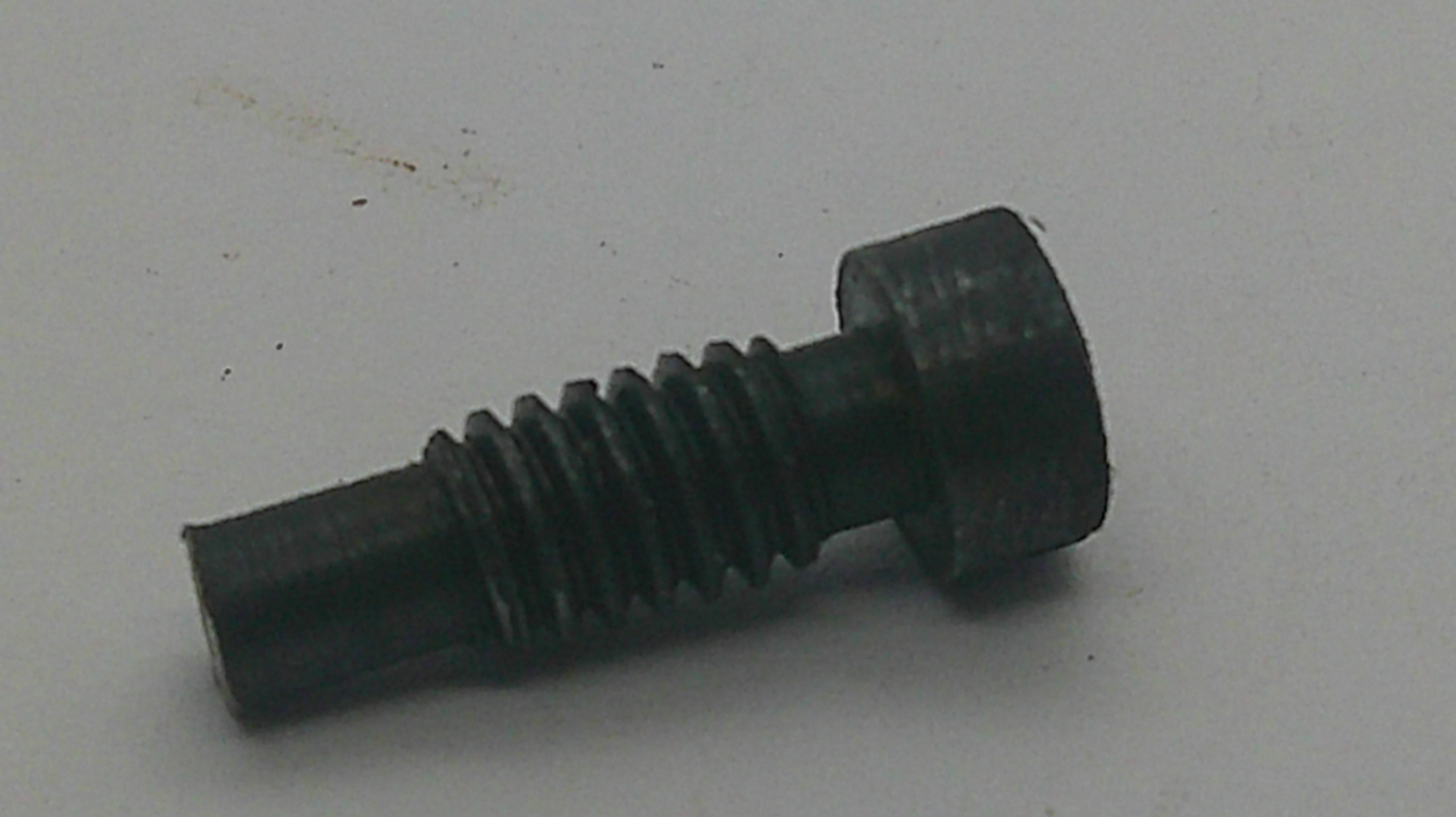 A small black metal threaded screw or bolt with a hexagonal head, photographed on a plain light gray surface.
