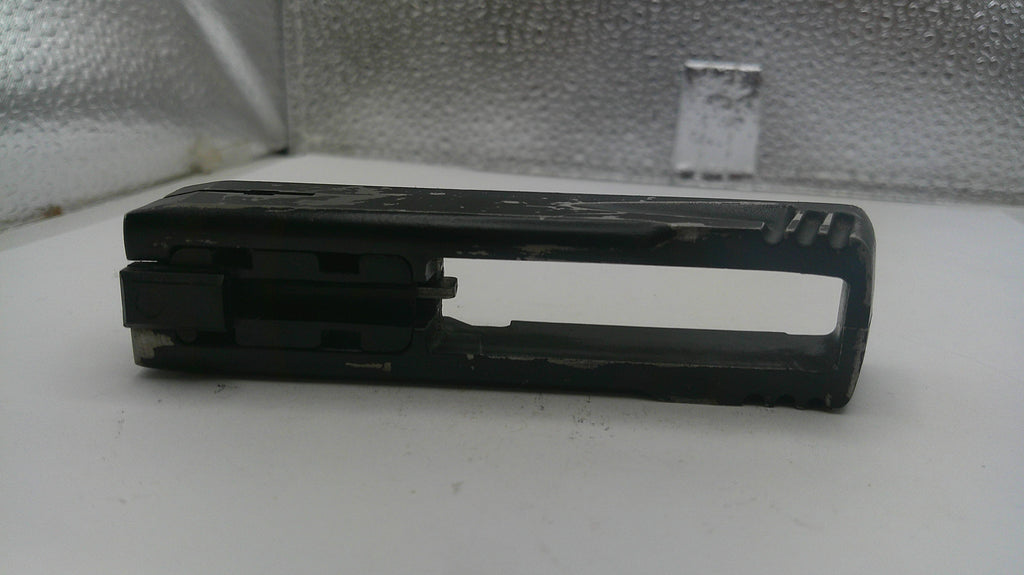Black plastic component on a white surface with a textured gray background