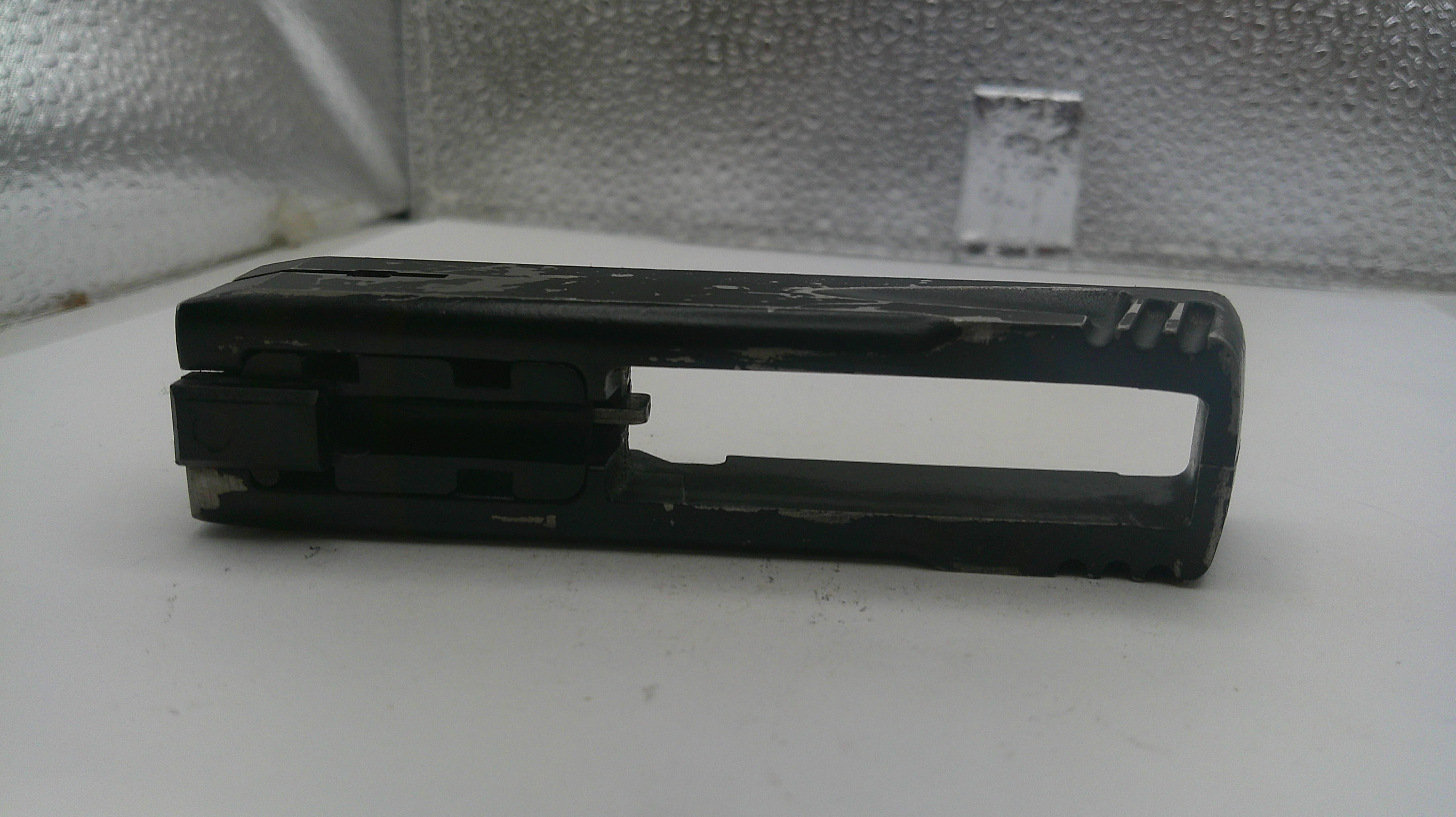 Black plastic component on a white surface with a textured gray background