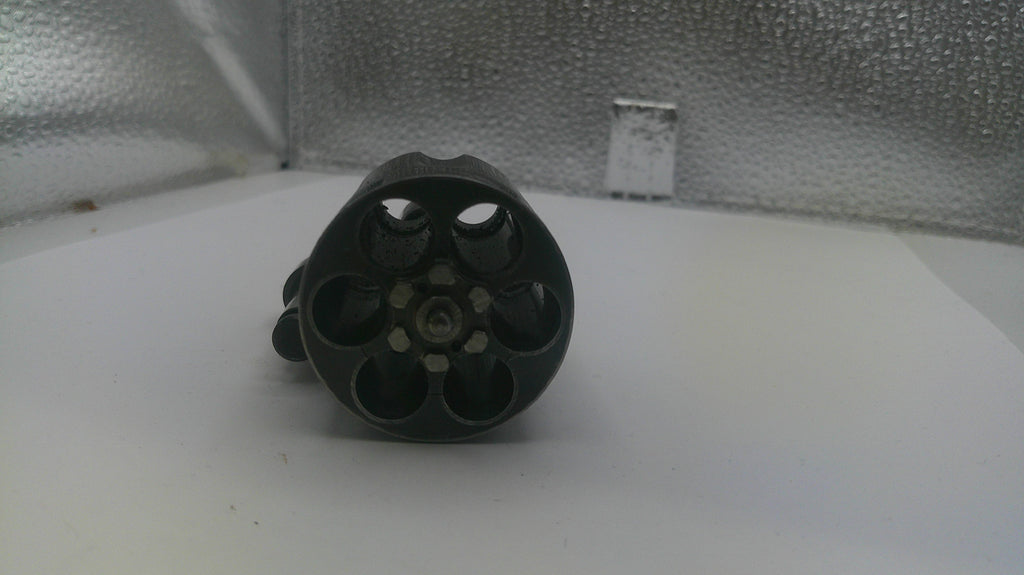 Black cylindrical object with multiple holes on a white surface with a metallic background