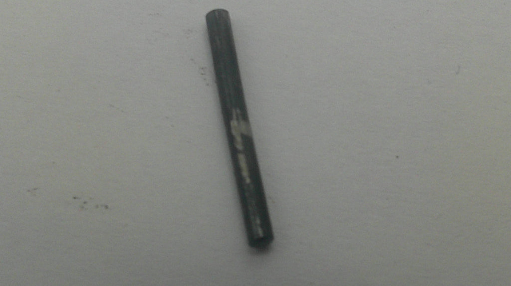 A single dark gray cylindrical rod or stick with a worn, scratched surface, placed vertically on a plain light gray background.