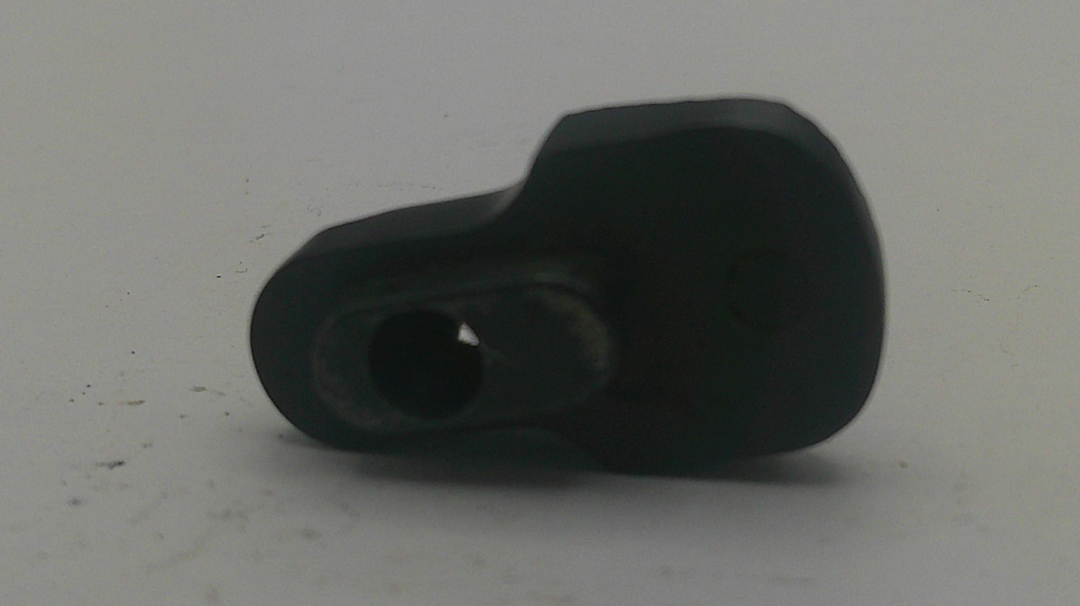 A small black plastic component with a circular opening, photographed on a plain light gray surface.