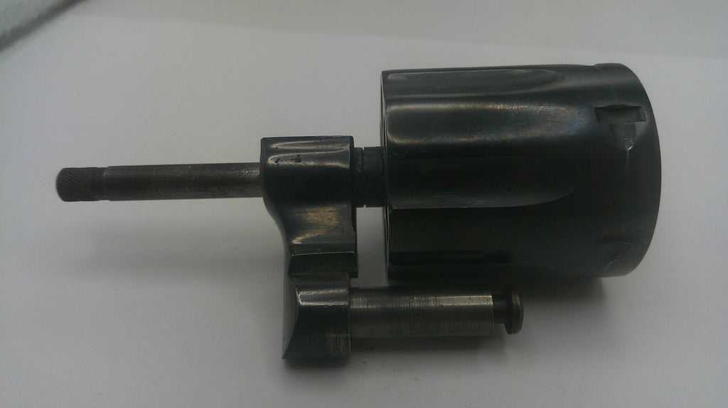 A dark metallic mechanical part, possibly a motorized tool component or valve solenoid, featuring a cylindrical body, a protruding shaft, and a short horizontal pin, shown on a plain light background.
