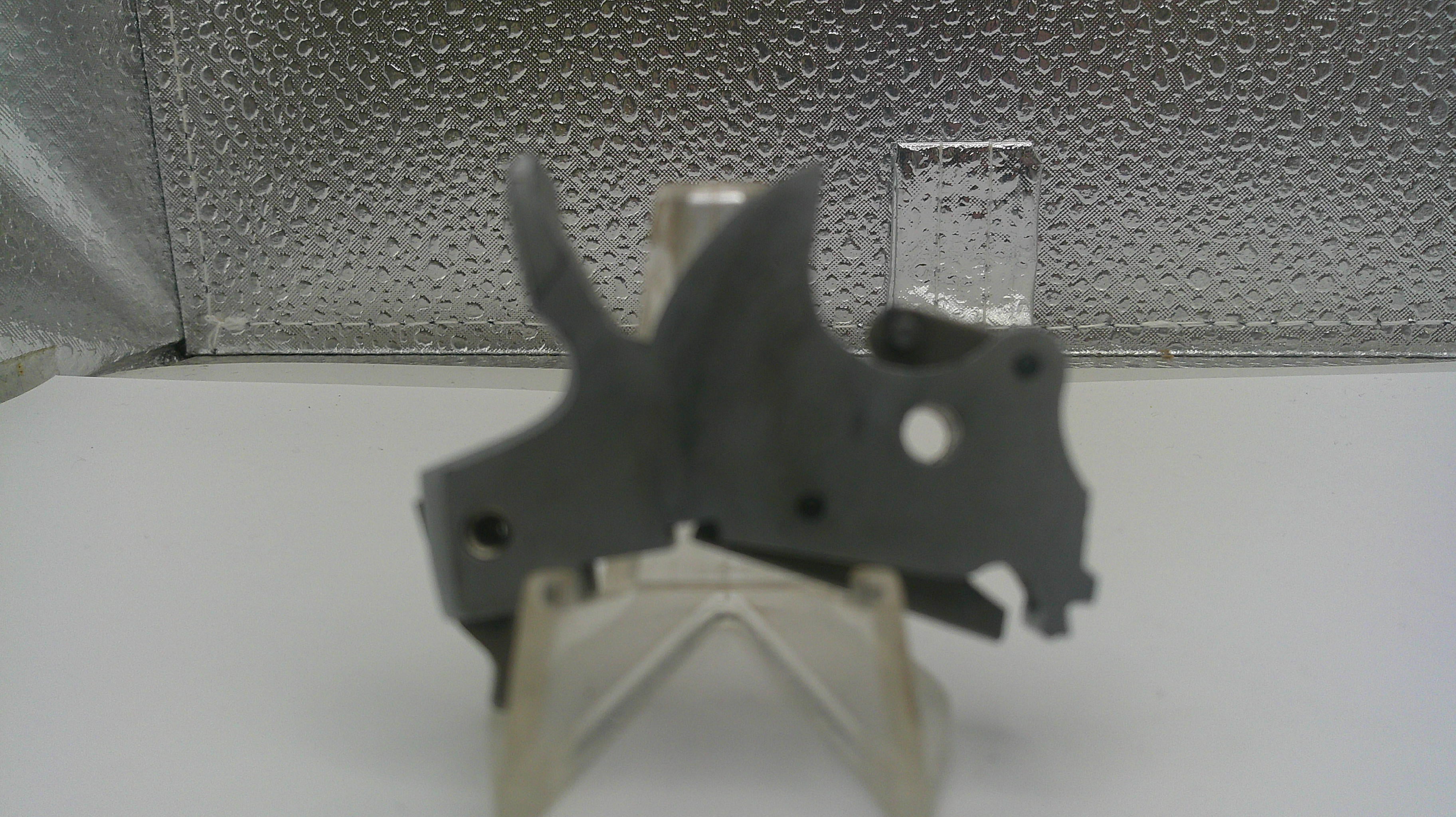 Metallic object on a stand against a textured silver background