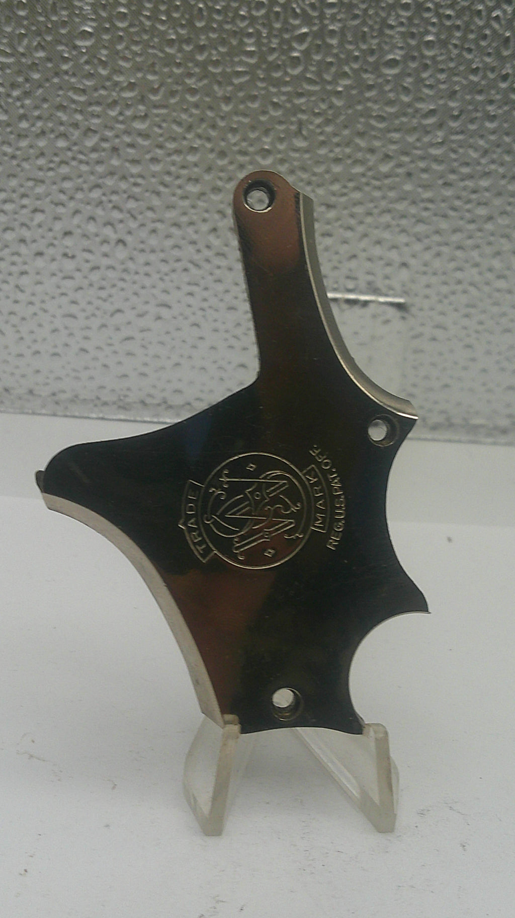 Metallic tool with a brand logo on a textured white background
