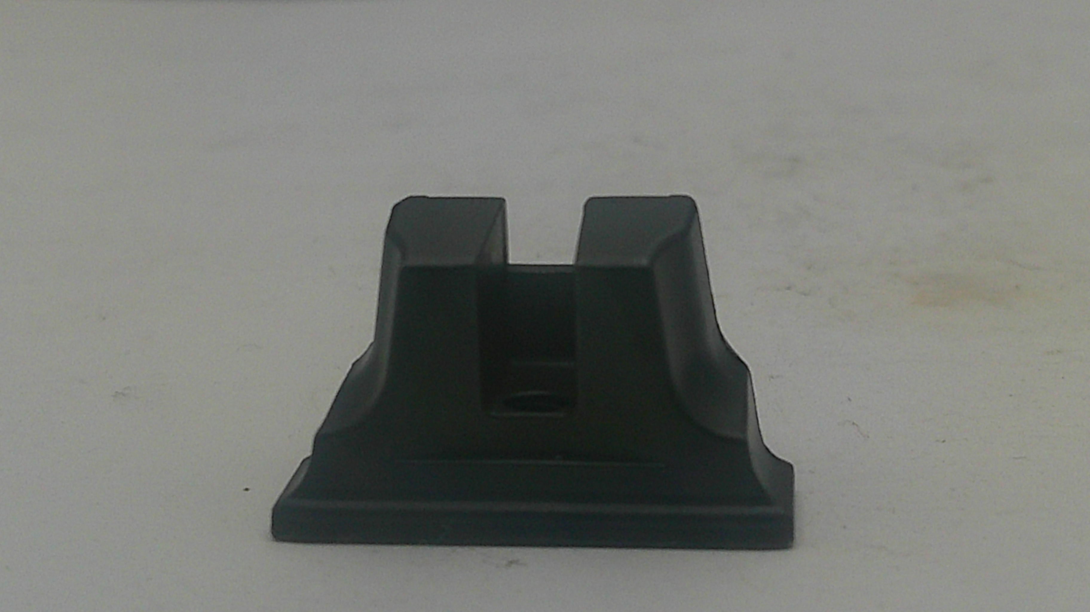 A black plastic or rubber mounting bracket or adapter piece with a rectangular base and two upright flanges, shown on a plain off-white surface.