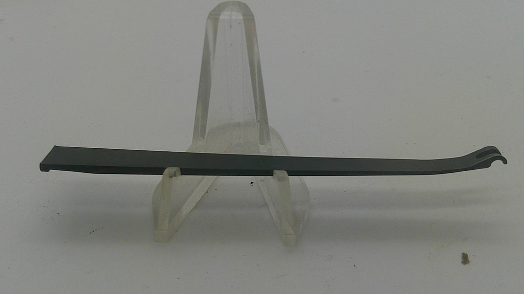 A long, thin black curved strip or blade-like component displayed horizontally on a clear plastic stand against a plain light gray background.