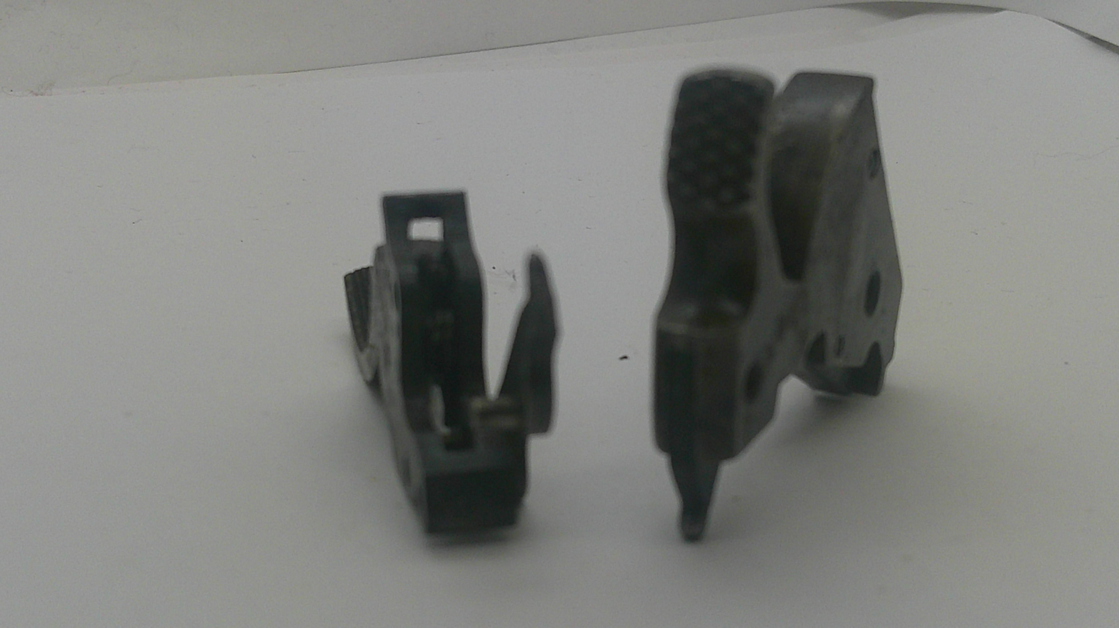 Two small black plastic mechanical components or clips shown on a plain white surface.