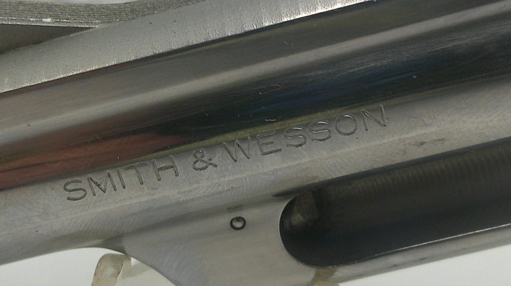 Close-up of a Smith & Wesson firearm with engraved text.