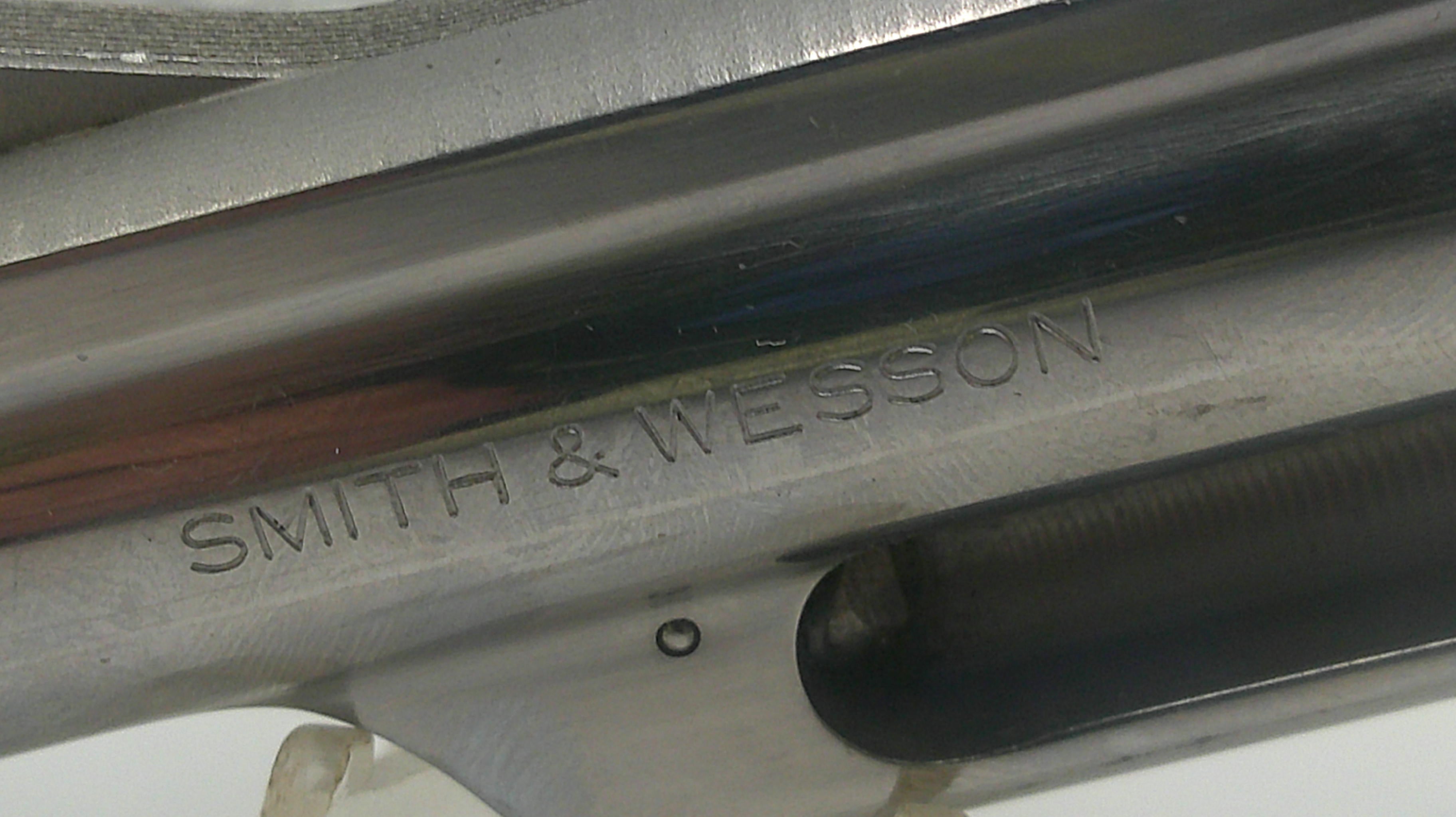 Close-up of a Smith & Wesson firearm with engraved text.
