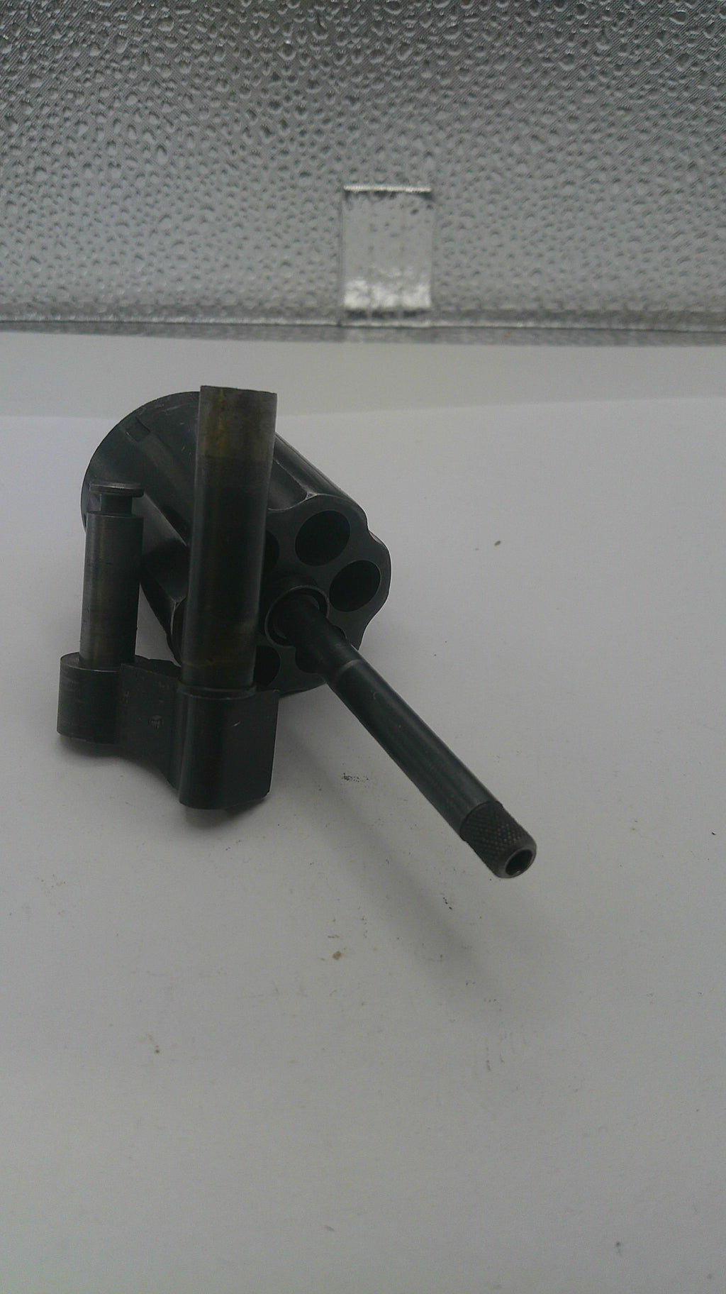 Black metal tool on a white surface with a textured gray background