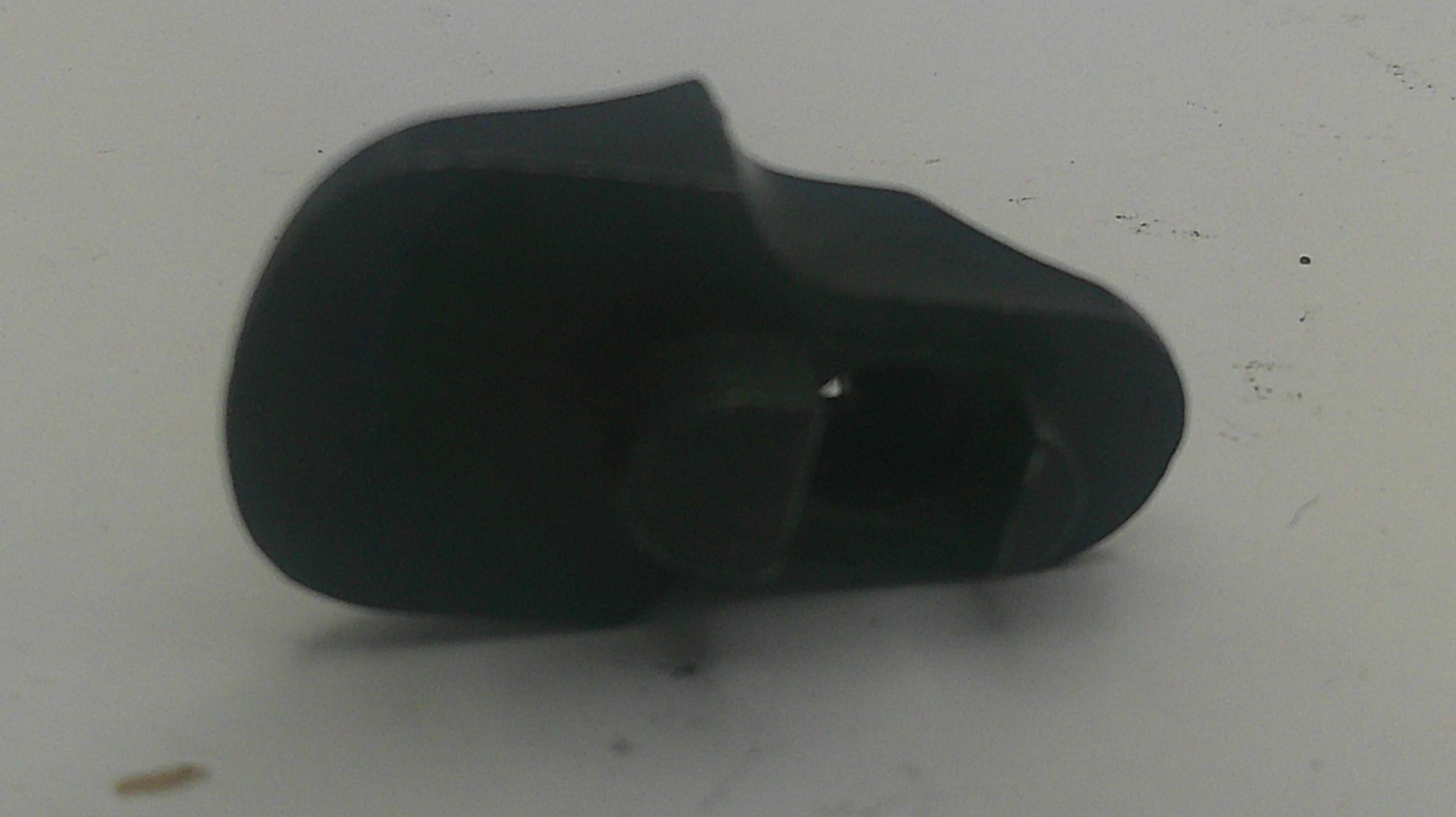A small black plastic component or cap with a rounded, tapered shape, shown on a plain off-white surface.