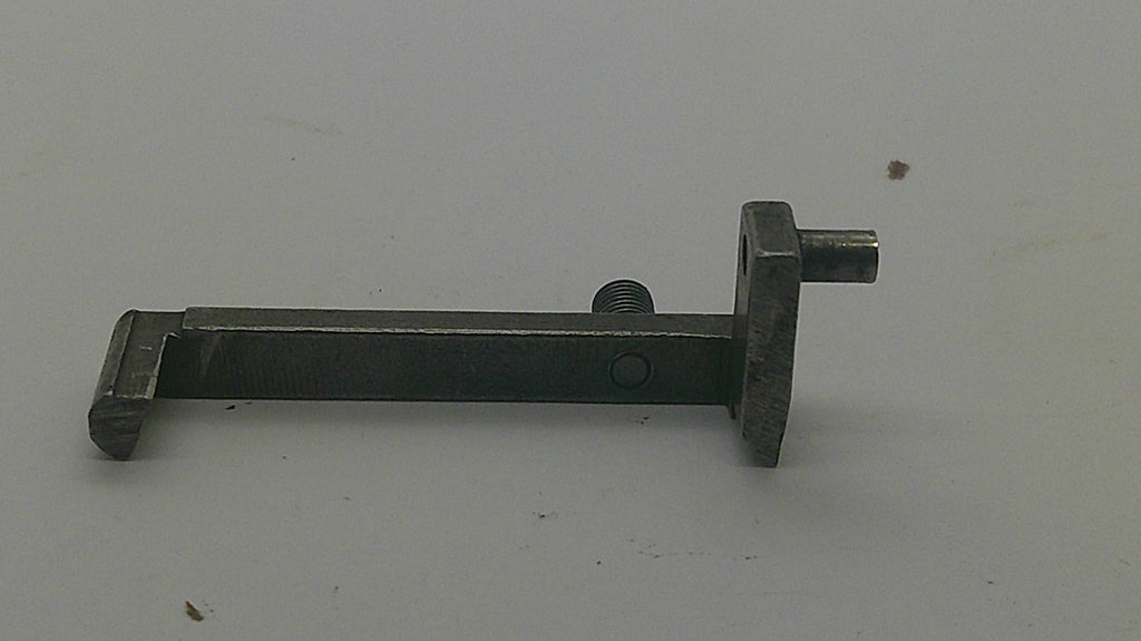 A dark metal latch or lock component with a rectangular plate and protruding bolt, photographed on a plain light background.