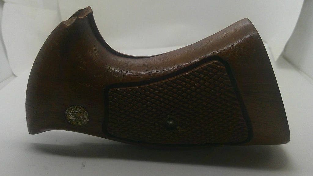 A brown wooden gunstock grip or handle component with a textured grip panel and a small brass screw detail, shown against a plain white background.