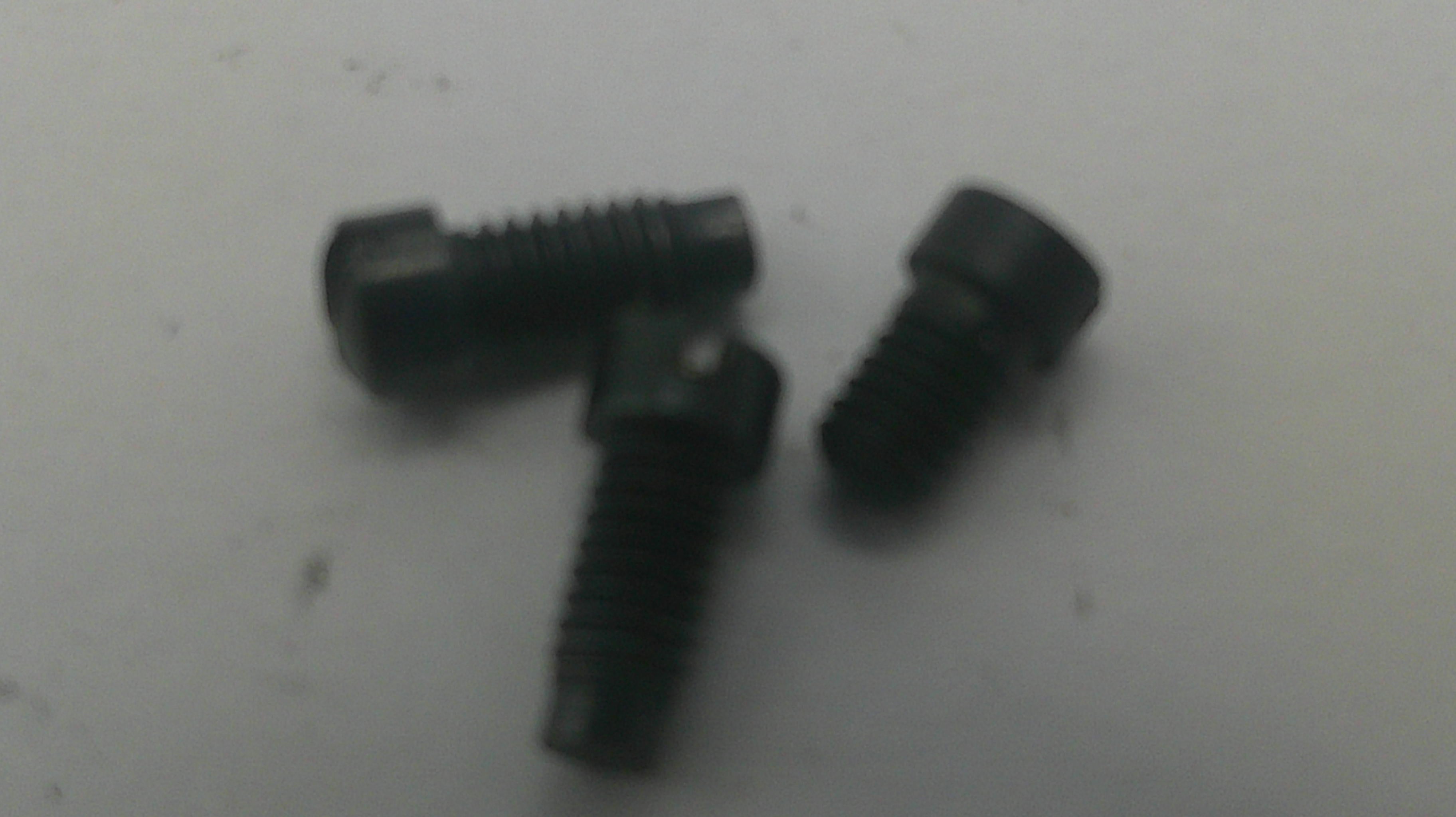 Three small black metal hex head screws with threaded shanks, photographed on a plain light background.