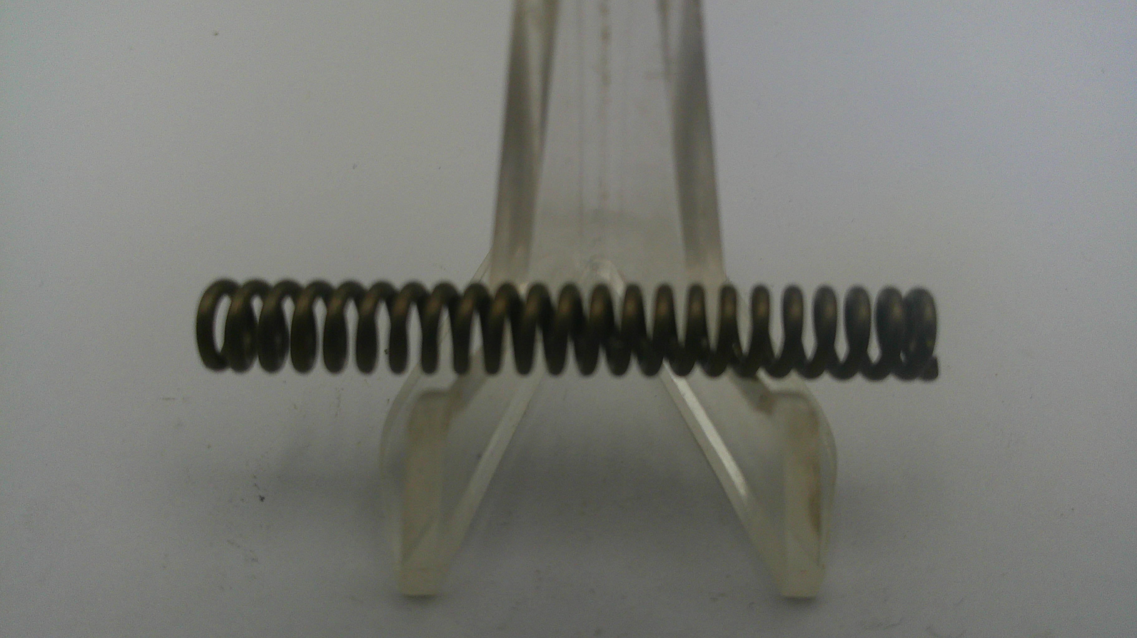 Metal spring on a clear stand against a white background