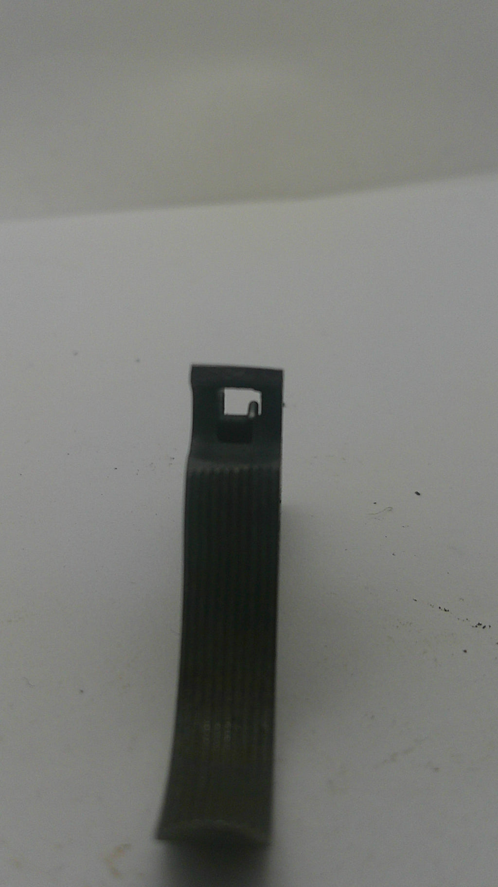A small black plastic or rubber strip-like component with a rectangular cutout, photographed against a plain off-white background.
