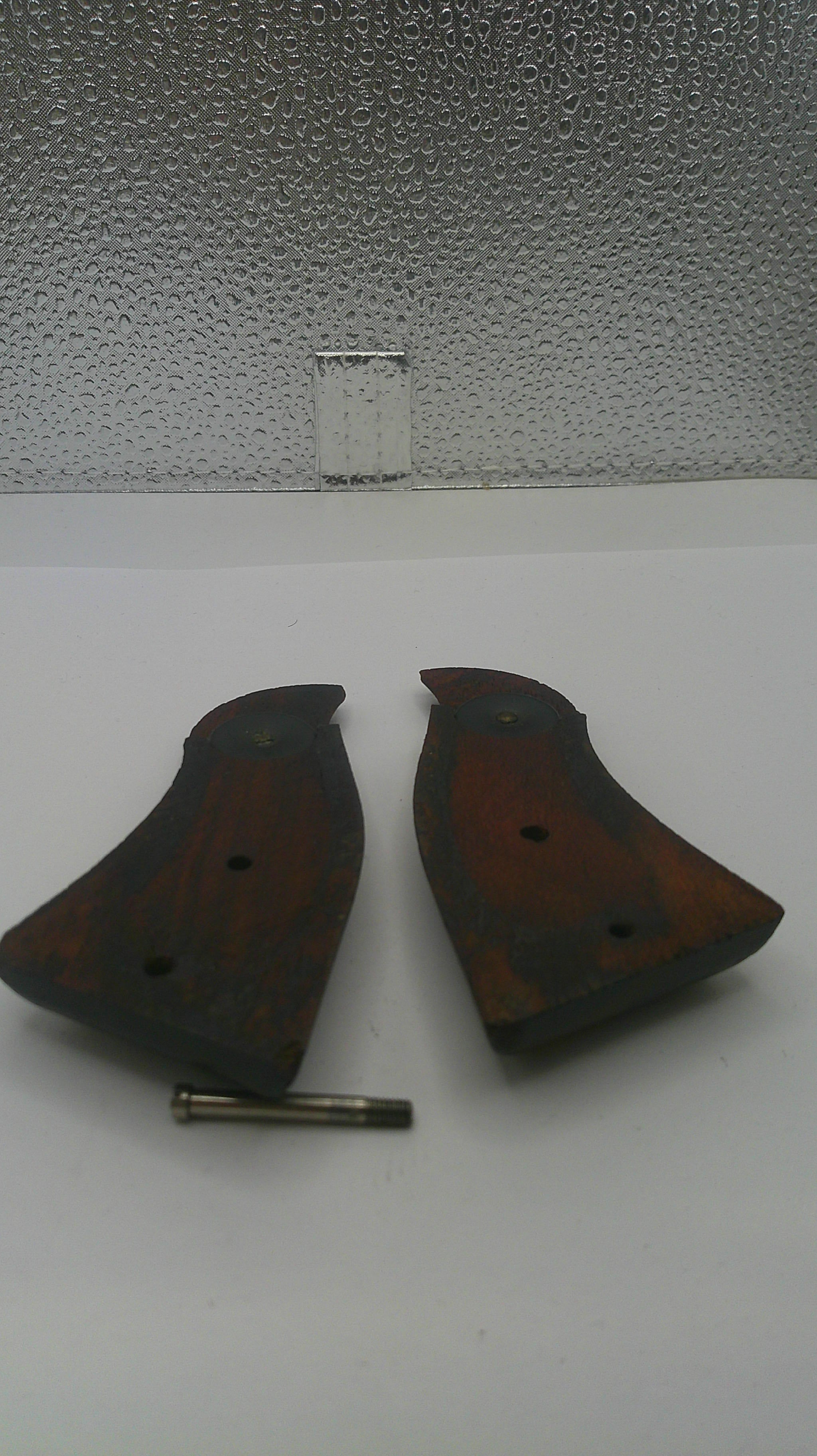 Two brown leather gun holsters with a metal clip on a textured white surface.