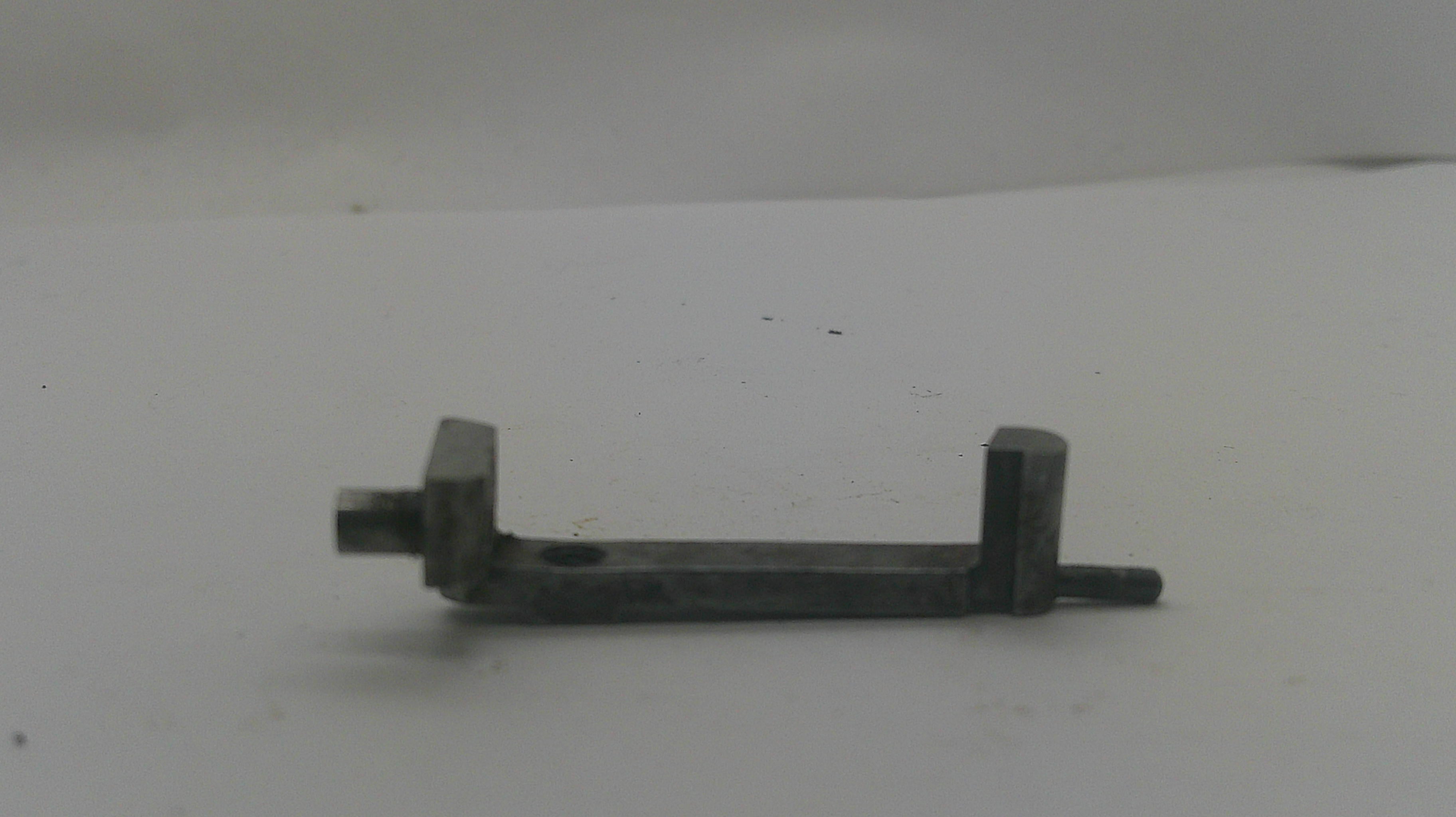 A small dark metal hardware piece with a flat rectangular bar, a left-side bolt protrusion, and a right-side bracket with a protruding bolt, shown on a plain light background.