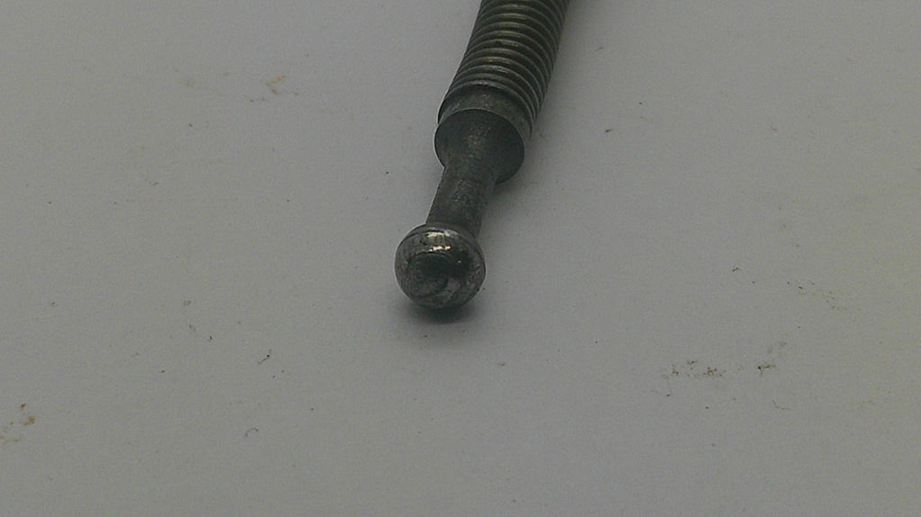 A close-up of a dark metal threaded rod or bolt with a spherical ball end, resting on a plain light gray surface.
