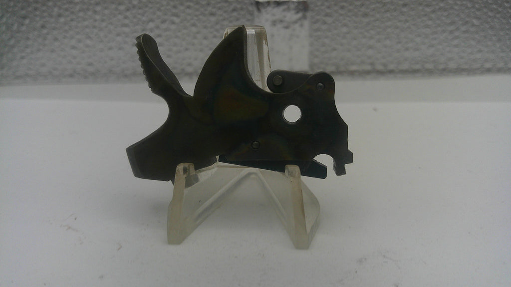 Black metal component on a white stand against a textured gray background